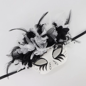 Detailed close-up of Day of the Dead mask with black feathers and white lace flowers
