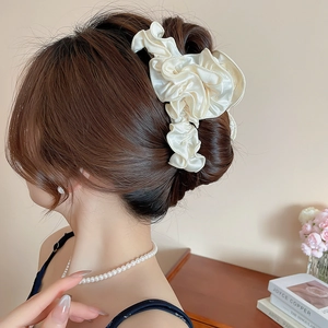 Detail of elegant beige pleated satin hair claw clip worn in a French style bun
