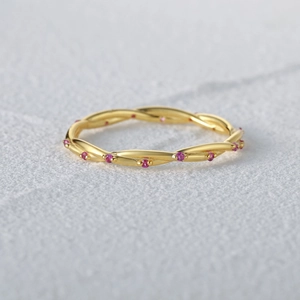 Macro shot of gold twisted rope ring featuring circular pink gemstones in sterling silver