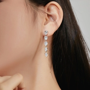Macro detail of long silver tassel earrings featuring five sparkling pear-cut zircon stones