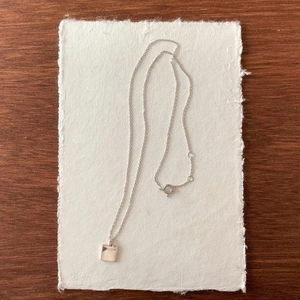 Detail of minimalist 925 sterling silver square pendant on a delicate polished chain