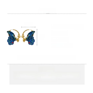 Detail showing oversized blue embroidered butterfly hoop earrings with rhinestones
