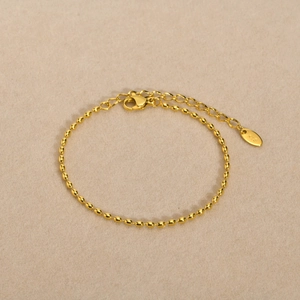 Detail of golden oval bead chain bracelet with lobster clasp and K18 heart tag