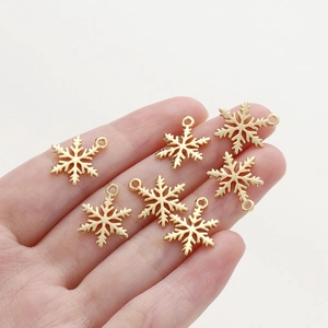18K gold-plated snowflake charms for DIY jewelry making held in hand for scale
