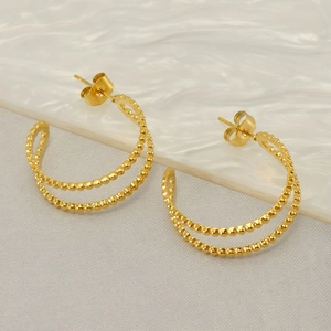 Minimalist double-row bead gold geometric C-shaped earrings on light gray fabric background
