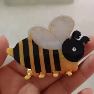 Close-up of cute bee hair claw clip with yellow and black acrylic finish and rhinestone