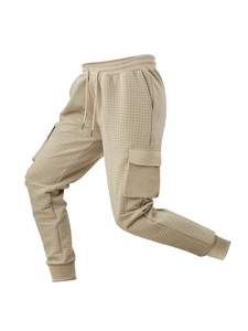 Detail of khaki quilted waffle fabric texture and cargo side pocket on men's trousers