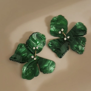 Close-up of green marble resin flower earrings with sparkling rhinestones and gold accents