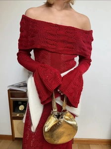 Detail of red hollowed-out knit dress showing off-shoulder neckline and bell sleeves