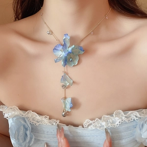 Detail of blue gradient fabric flower necklace with crystal beads on a female model