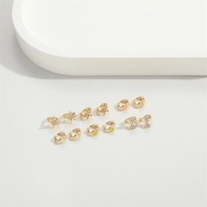 Close-up of assorted gold mini hoop earrings with star, smile, and bow charms