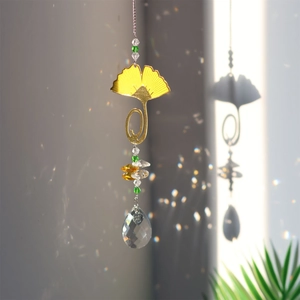 Detail of crystal suncatcher with yellow ginkgo leaf casting rainbow light on wall