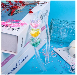 Detail of clear headband with three heart-shaped containers filled with colorful sequins