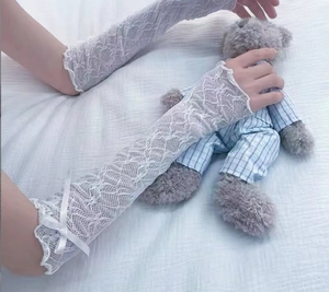 Close-up of white lace arm sleeves with silk bows and delicate mesh floral texture