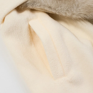 Détail d'un manteau en fausse fourrure blanc cassé avec col pelucheux et poche latérale