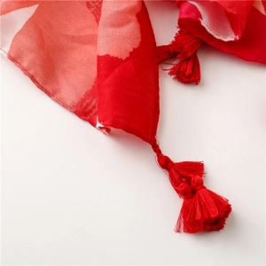 Macro shot of red floral scarf with detailed stitching and red tassel fringe detail