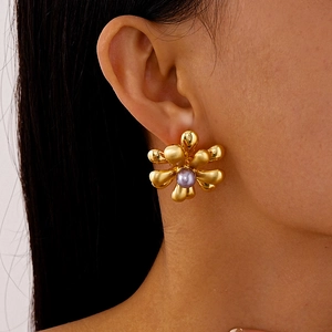 Gros plan détaillé d'un clou d'oreille fleur dorée avec perle mauve sur mannequin