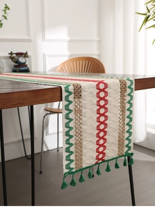 Close-up of woven table runner featuring red and green geometric patterns with green tassels