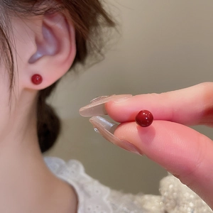 Detailed view of red bead stud earrings with gold plating and silver needles for women
