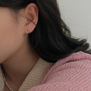 Close-up of minimalist polished silver heart stud earrings worn by a model