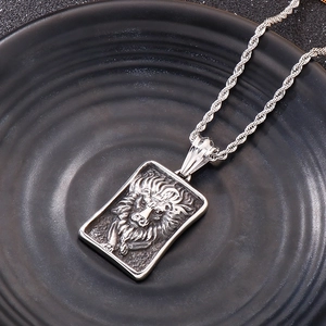 Détail d'un pendentif tête de lion rétro en acier sur un plateau noir ondulé