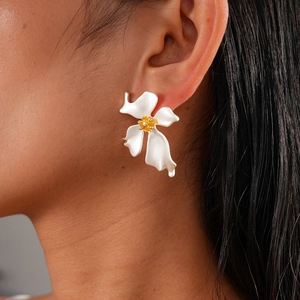Detailaufnahme weißer Blumenohrring mit goldenem Stempel getragen im Vintage-Stil