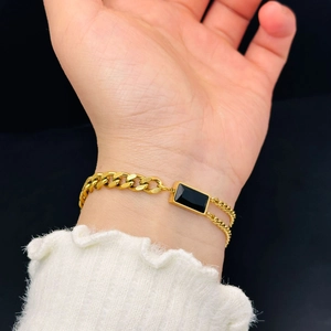 Elegant gold-plated chain bracelet with a rectangular black gemstone on model's wrist