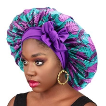 Detail of teal satin bonnet with purple leaf print and decorative purple bow