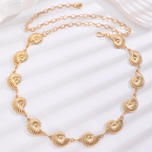 Detail view of golden nautilus shell chain belt with textured relief on white background