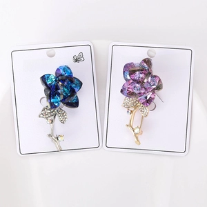 Detailed view of blue and purple crystal flower brooches with diamond-encrusted leaves