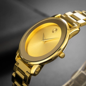 Macro shot of minimalist gold watch dial with a single dot and polished metal band
