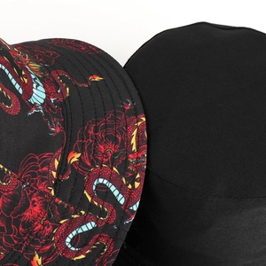 Dettaglio di un cappello da pescatore nero con stampa di drago rosso e trama tessile