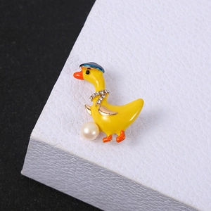 Macro detail of cute yellow duck brooch with sparkling rhinestones and white pearl