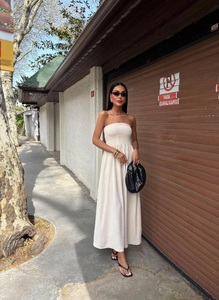 Detail of elegant tube maxi dress with elastic high waist and flowy cream fabric