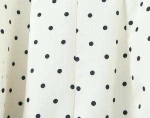 Close-up of white fabric with black polka dots showing detailed textile texture