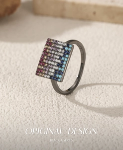 Macro detail of pixel-style black metal ring with multi-colored crystals and turquoise