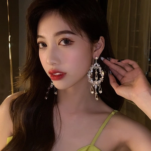Close-up of vintage gold oversized rhinestone drop earrings worn by a model