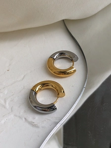 Macro view of two-tone gold and silver hoop earrings with a polished metallic mirror finish