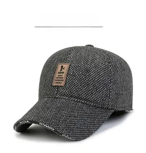 Detail of gray knitted baseball cap featuring brown leather patch and brand printing
