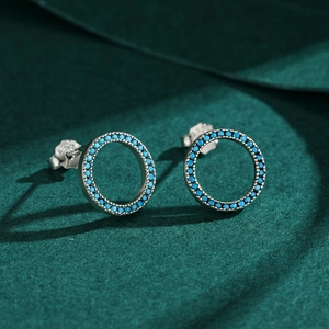 Elegant s925 silver hollow round stud earrings with turquoise stones on green fabric