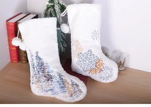Detail of white plush Christmas stockings with snowflake embroidery and soft pompom accents