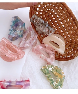 Detailed collection of assorted colorful acetate hair claws in a rustic woven basket