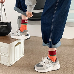 Close-up of stylish contrast color crew socks with letter patch and retro sneakers