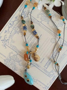 Detailed shot of ethnic beaded necklace with turquoise evil eye pendant and woven cord