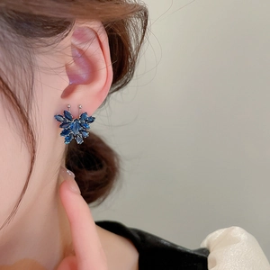 Dettaglio dell'orecchino a farfalla con zirconi blu navy indossato su orecchio modello
