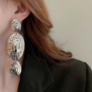 Detail of silver long drop earrings with triple hammered oval metal disks on model