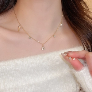 Detail view of gold-plated necklace with pearl, key and lock charms with matching studs
