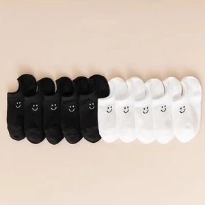 Flat lay of black and white ankle socks with minimalist embroidered smile face on heel