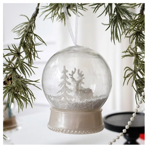 Detail of a white Christmas snow globe ornament with a miniature reindeer and pine forest
