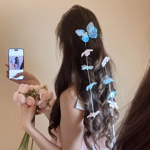Detailed view of light blue mesh butterfly hair clip with floral tassel on long wavy hair
